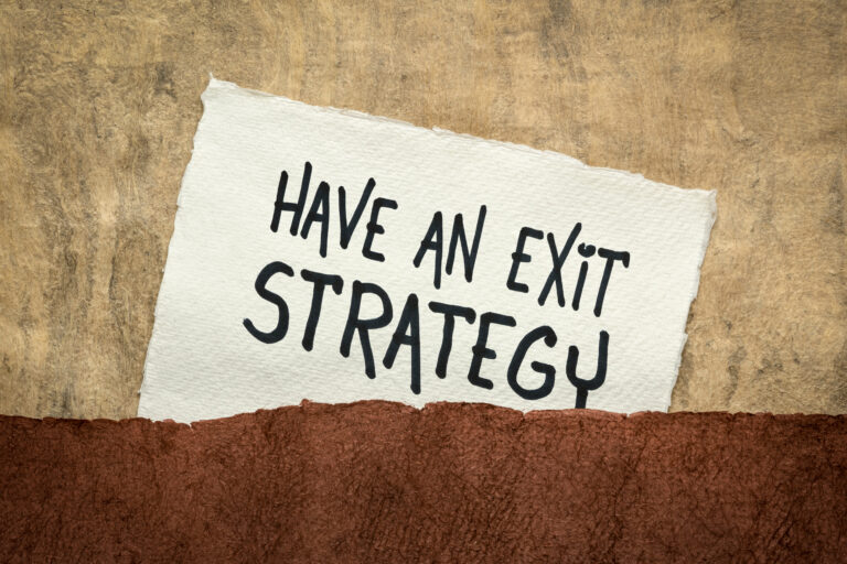 A piece of torn paper with the words “Have an Exit Strategy” written in bold, placed against a textured background. The image visually emphasizes the importance of planning and communicating a well-structured exit strategy when transitioning out of a business.