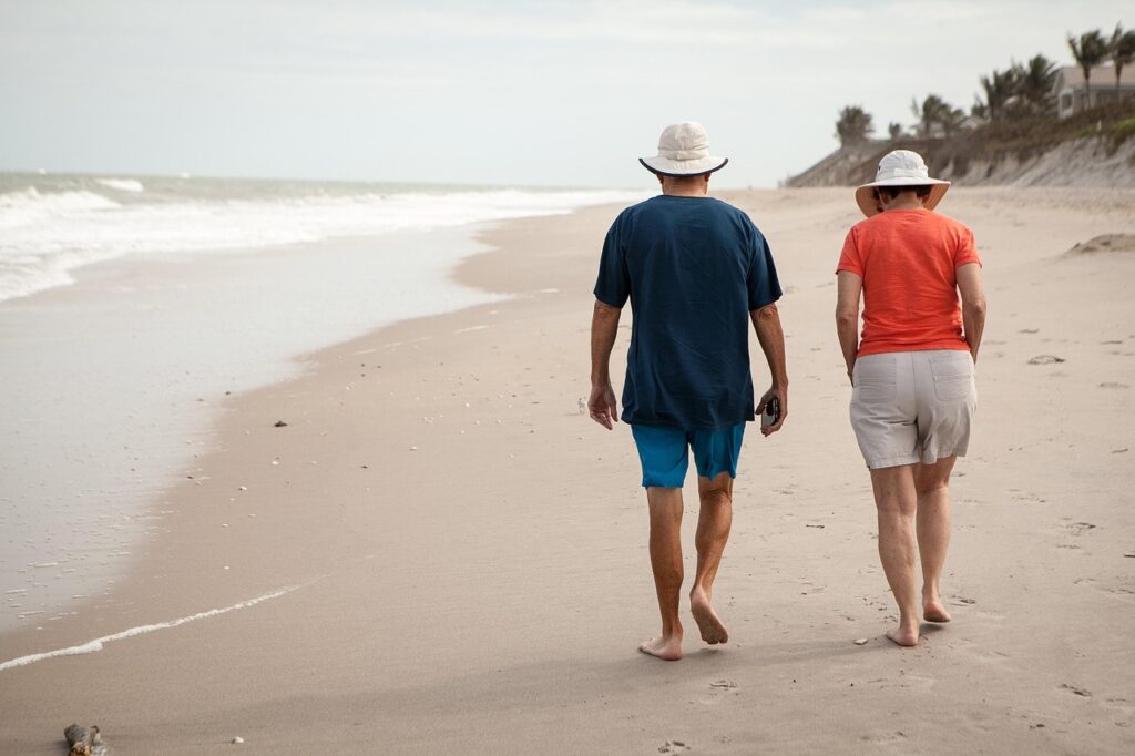 An older couple walks barefoot along a peaceful beach, symbolizing the reward of a well-timed and well-planned business exit. The image conveys retirement, freedom, and the personal fulfillment that comes from selling a business on your own terms.