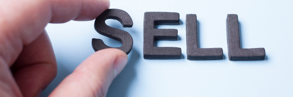 A close-up of a hand placing the final letter in the word "SELL," symbolizing the critical decision to exit a business. The image visually reinforces the importance of planning, preparation, and structure in maximizing net proceeds from a business sale.
