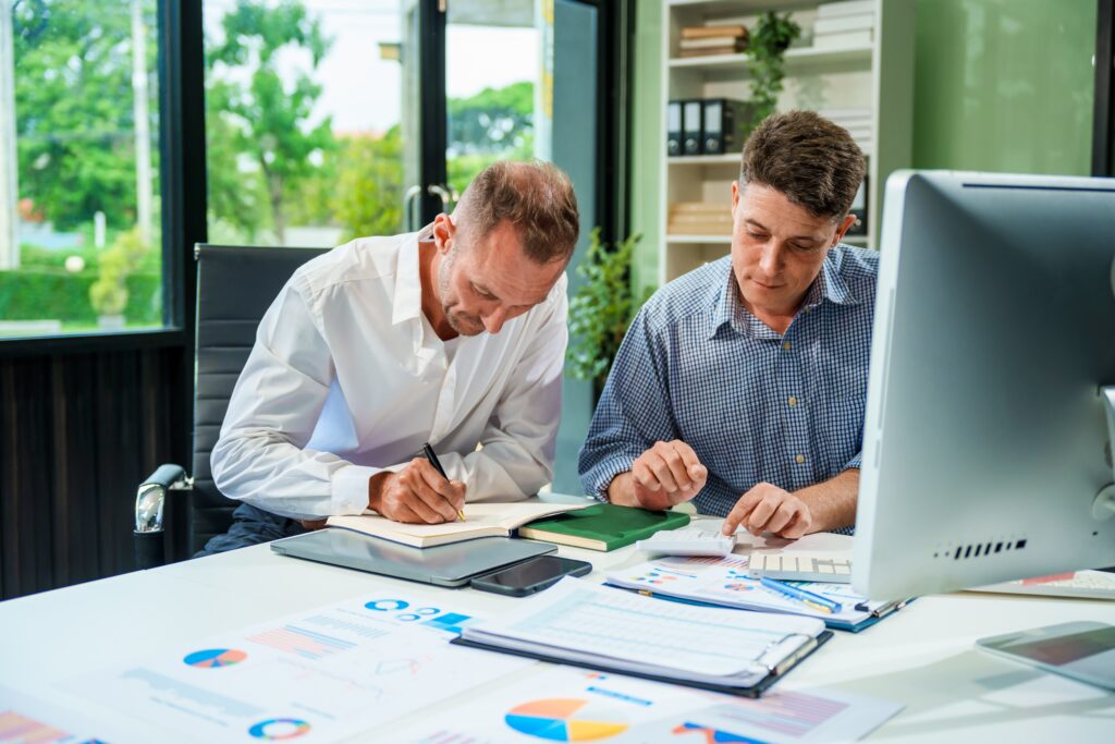 Two colleagues analyzing business financials and sale documents, representing the due diligence and planning required for internal business sales.