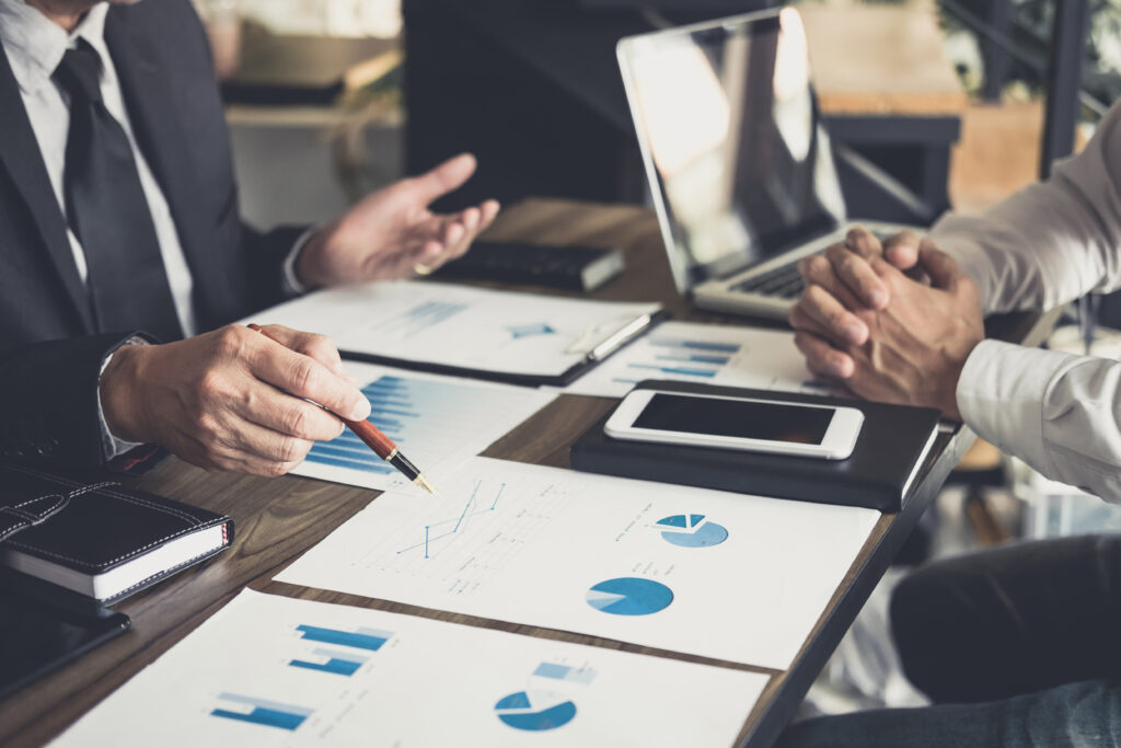 Business professionals discussing financial performance and valuation metrics, highlighting the importance of structured deals and third-party input in business transitions.