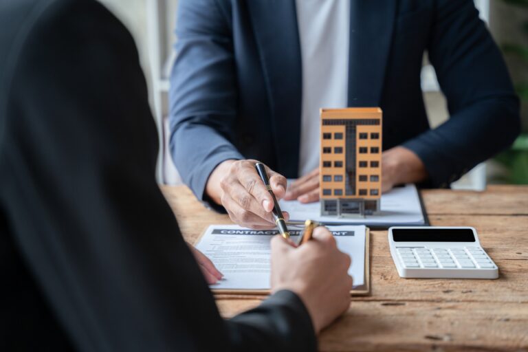 Business owner signing a contract for commercial property while discussing ownership options, highlighting the strategic choice between buying and leasing their building.