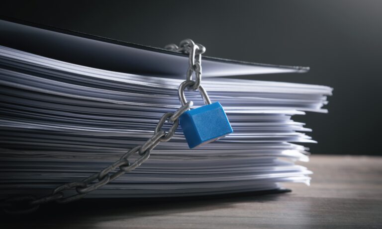 A thick stack of business documents secured tightly with a metal chain and blue padlock, symbolizing confidentiality and the protection of sensitive information during the sale of a business.