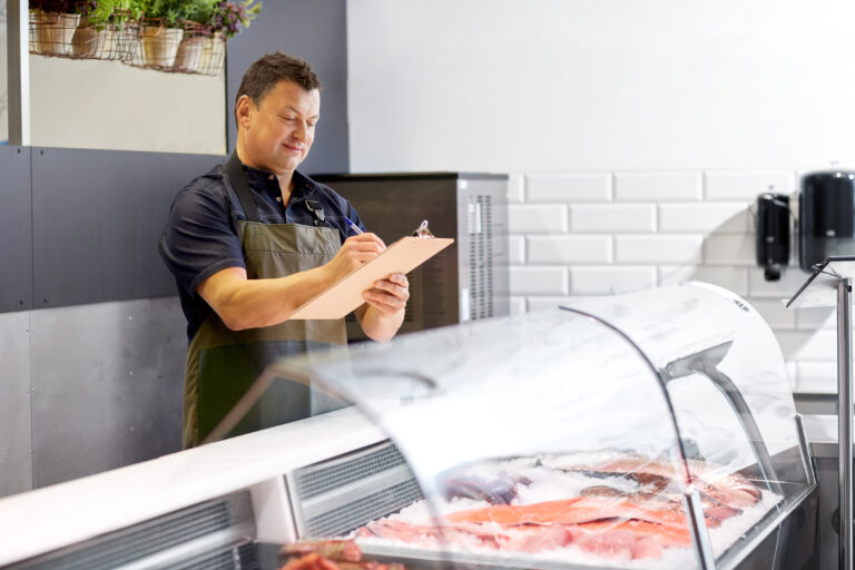 Business owner inspecting fresh seafood inventory and documenting operations, demonstrating strong systems and financial oversight to maximize business value before sale