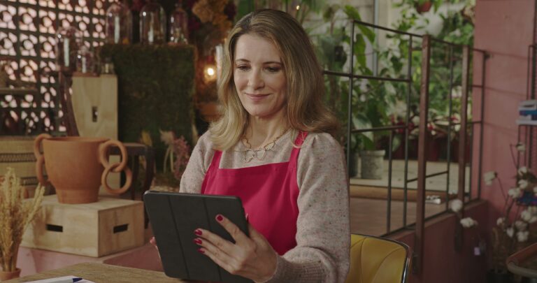 Female small business owner reviewing operations and financial data on a tablet inside a modern boutique workspace, representing business valuation preparation, operational independence, and building enterprise value before selling a company.