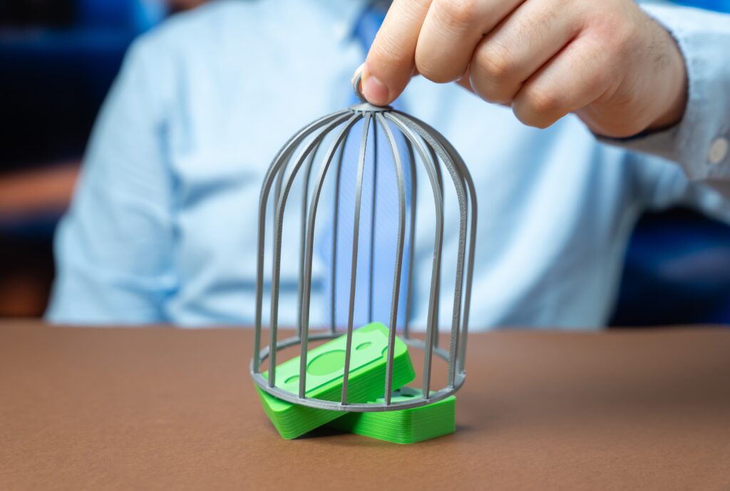 Business owner placing a protective cage over money, symbolizing how an escrow account protects buyer and seller funds during a business sale or M&A transaction.